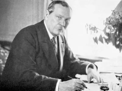 Arthur Conan Doyle writing at a desk