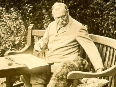 Arthur Conan Doyle writing outside on a bench.