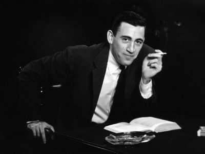 J.D. Salinger smoking a cigarette while reading a book