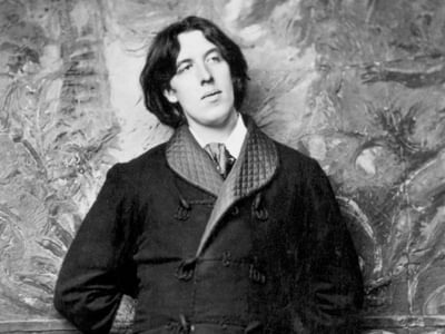 A black and white photo of Oscar Wilde wearing a stylish coat, exuding a classic and timeless vibe.