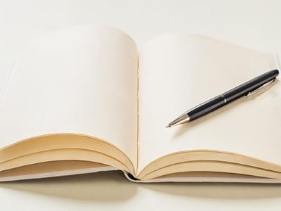 Open blank notebook with a black pen placed diagonally across its pages.