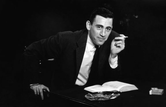 J.D. Salinger smoking a cigarette while reading a book