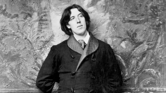 A black and white photo of Oscar Wilde wearing a stylish coat, exuding a classic and timeless vibe.